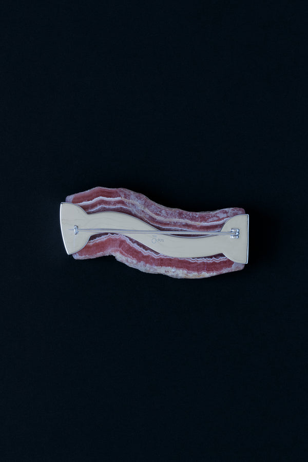 Back view of Rhodochrosite Slab cut to look like a piece of bacon set in a sterling silver brooch pin on black background
