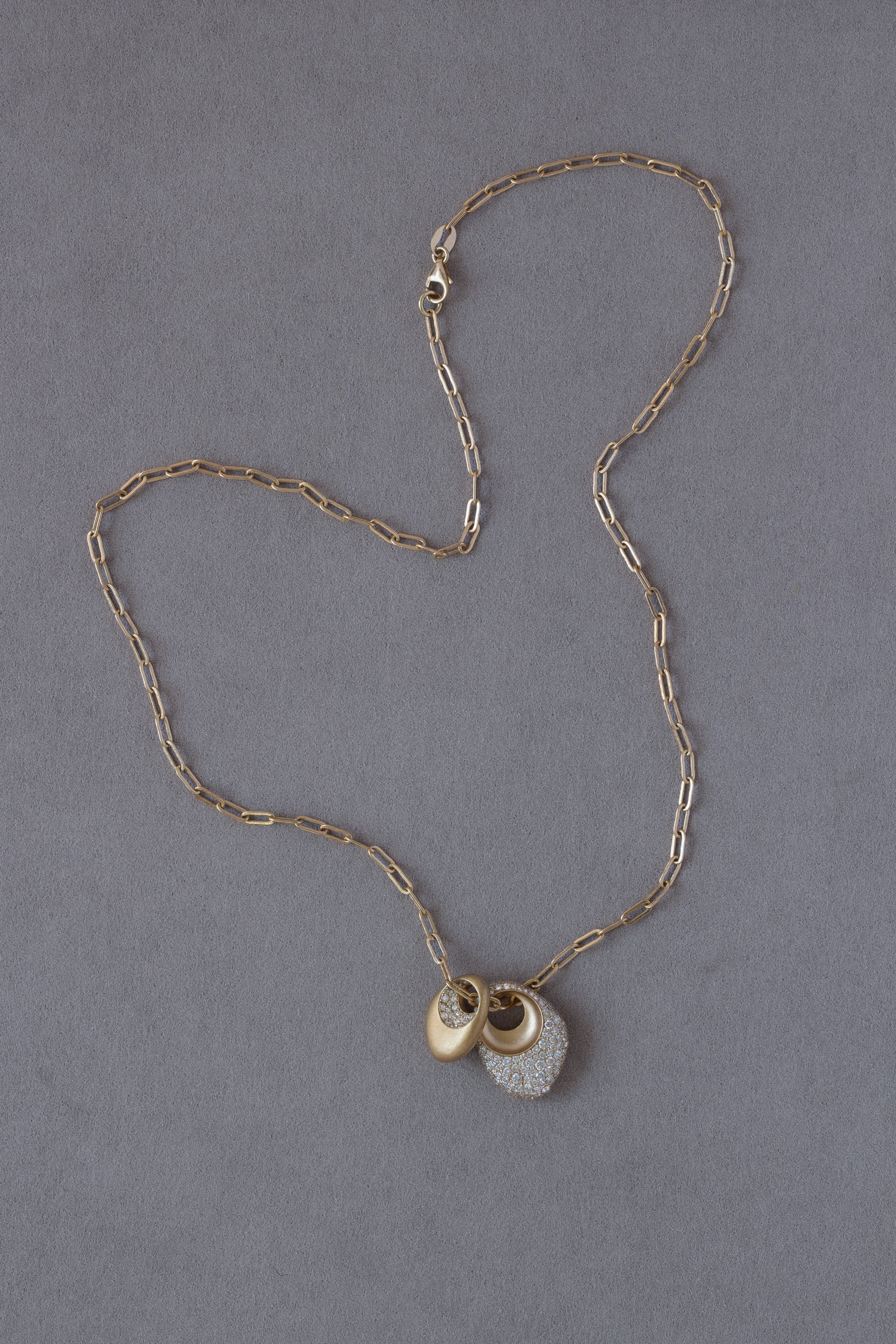 Pair of 18k Gold Egg Shaped Drop Pendants set with white diamonds on a grey background