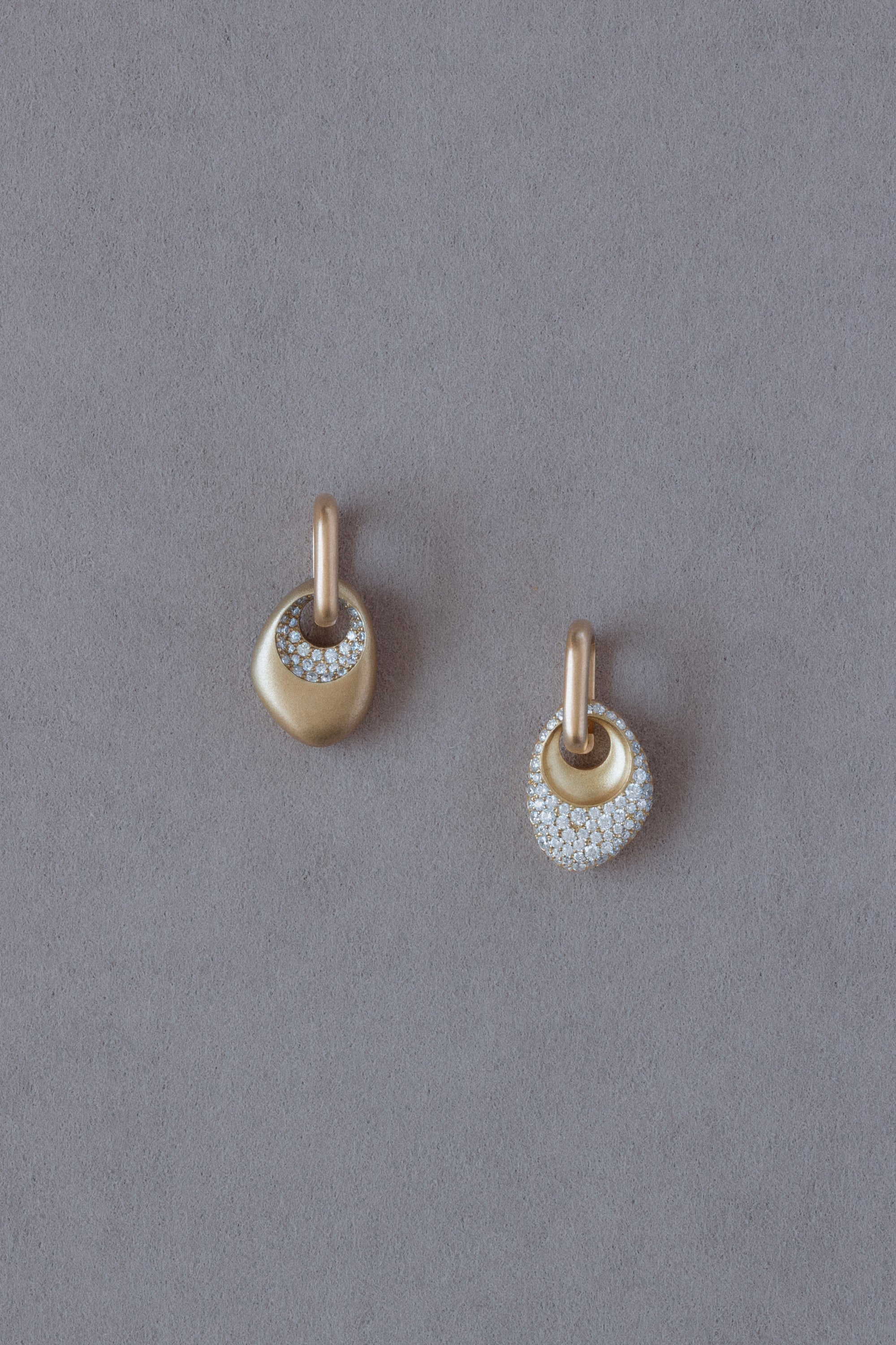 Pair of 18k Gold Egg Shaped Drop Earrings  set with white diamonds on a grey background
