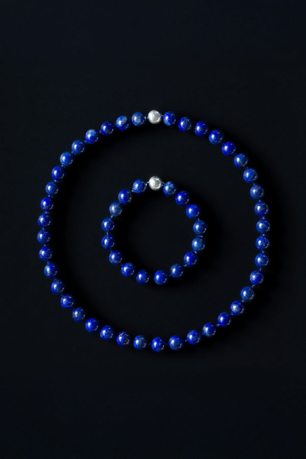 A set of lapis lazuli beaded necklace and bracelet with sterling silver magnetic clasps, displayed on a dark background.
