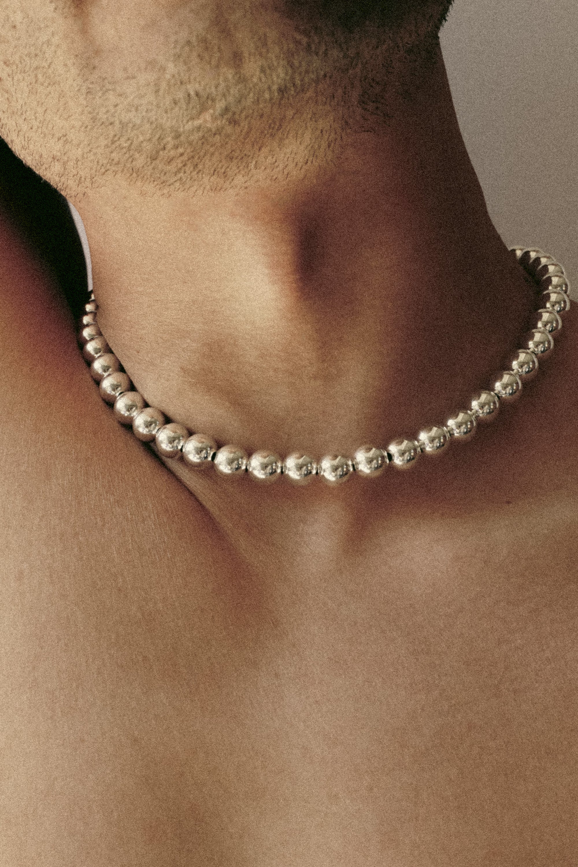 Silver beaded necklace on male model