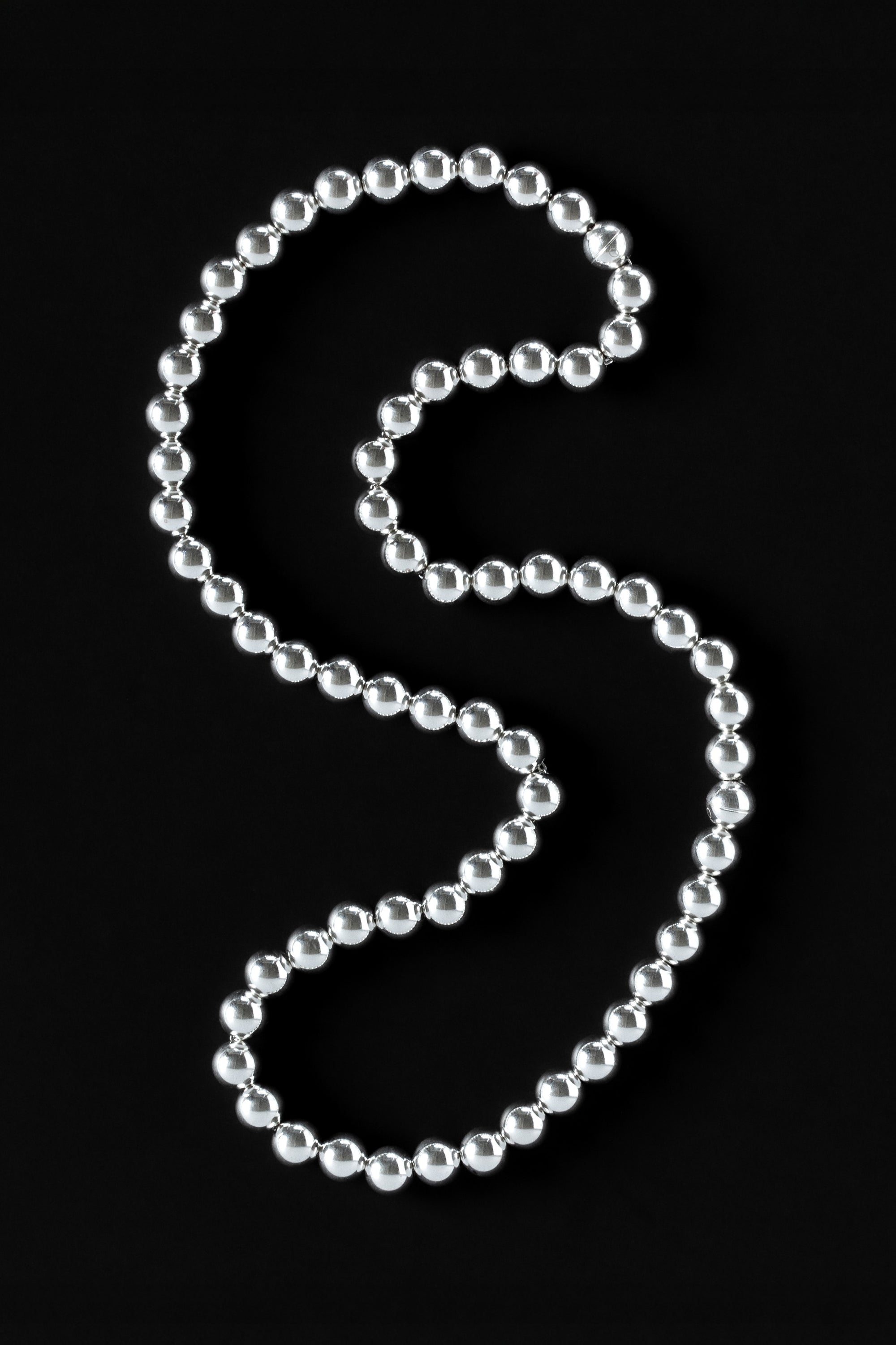 Long silver beaded necklace with magnetic clasp on black background
