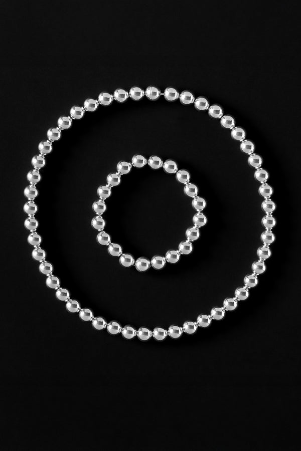 Set of silver beaded necklace and bracelets with magnetic clasp on a black background