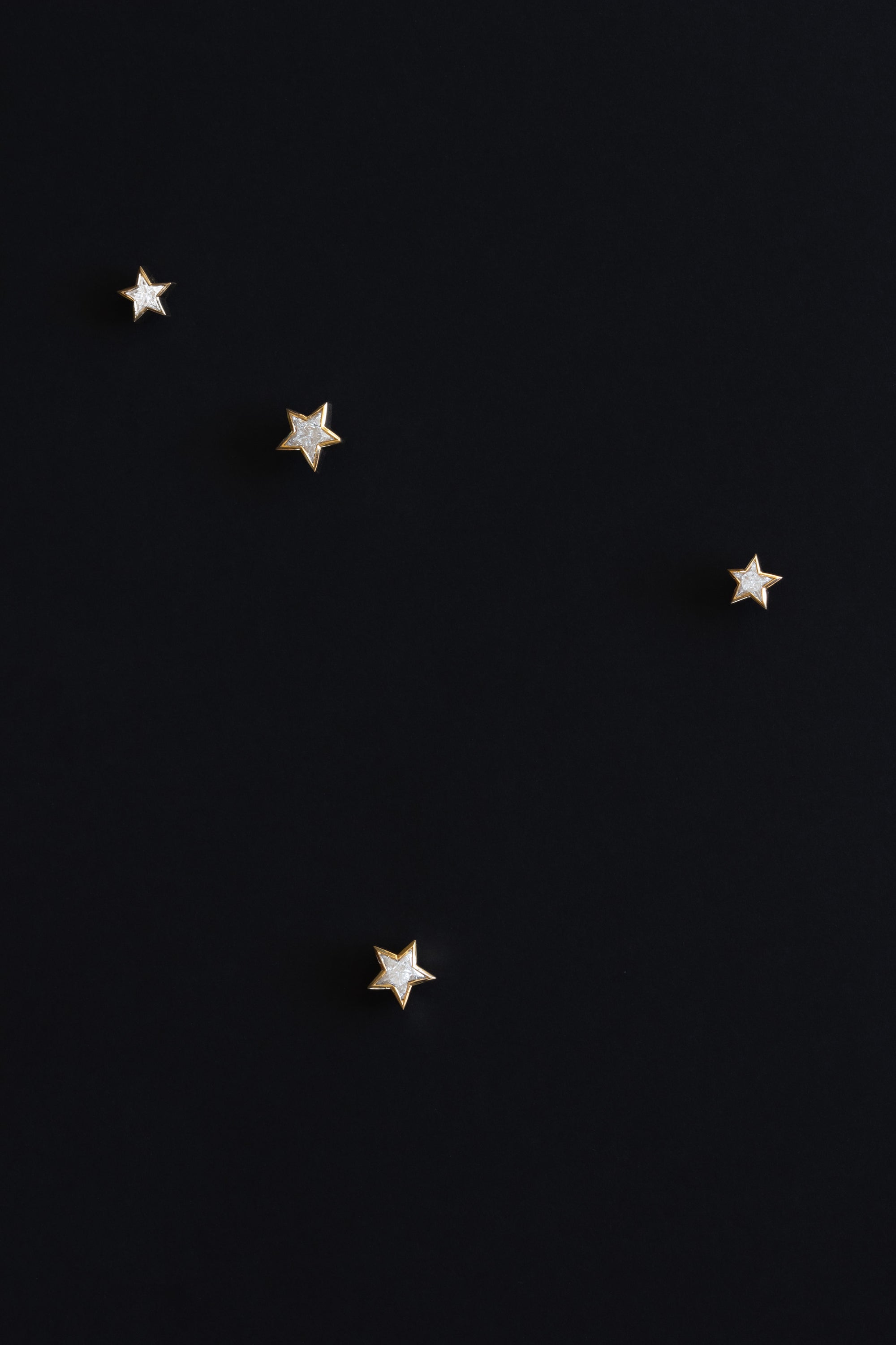Ouvelle Custom cut star shaped white diamond earrings set in 18 karat yellow gold on black background