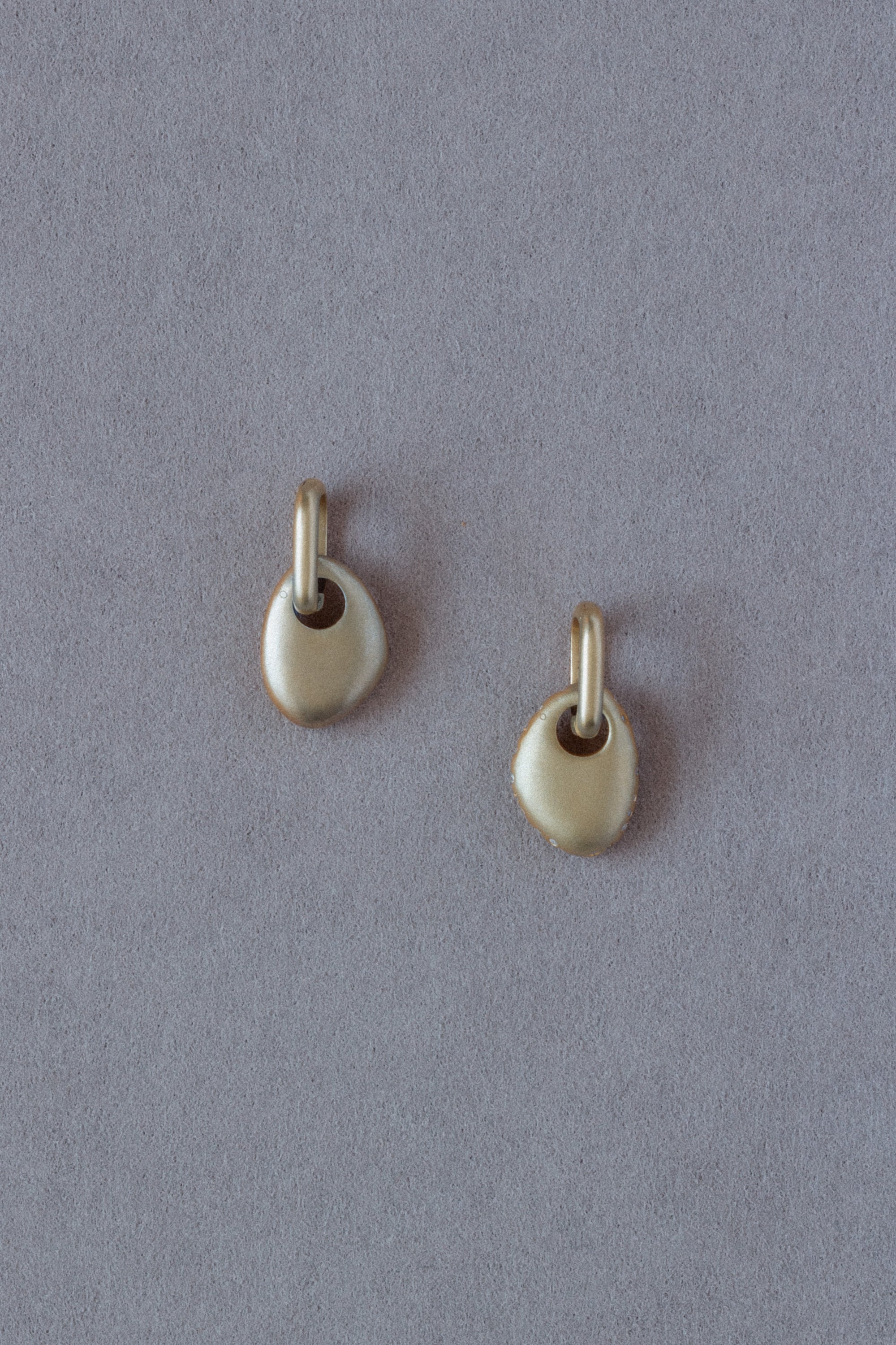 Pair of 18k Gold Egg Shaped Drop Earrings  set with white diamonds on a grey background back view

