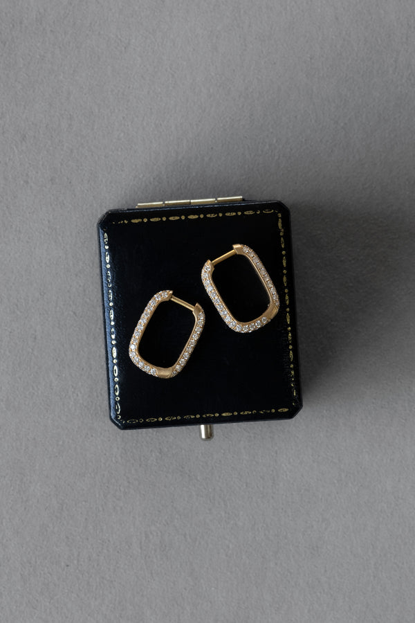 Ouvelle pair of gold and diamond pave rectangular rounded hoops on top of black box