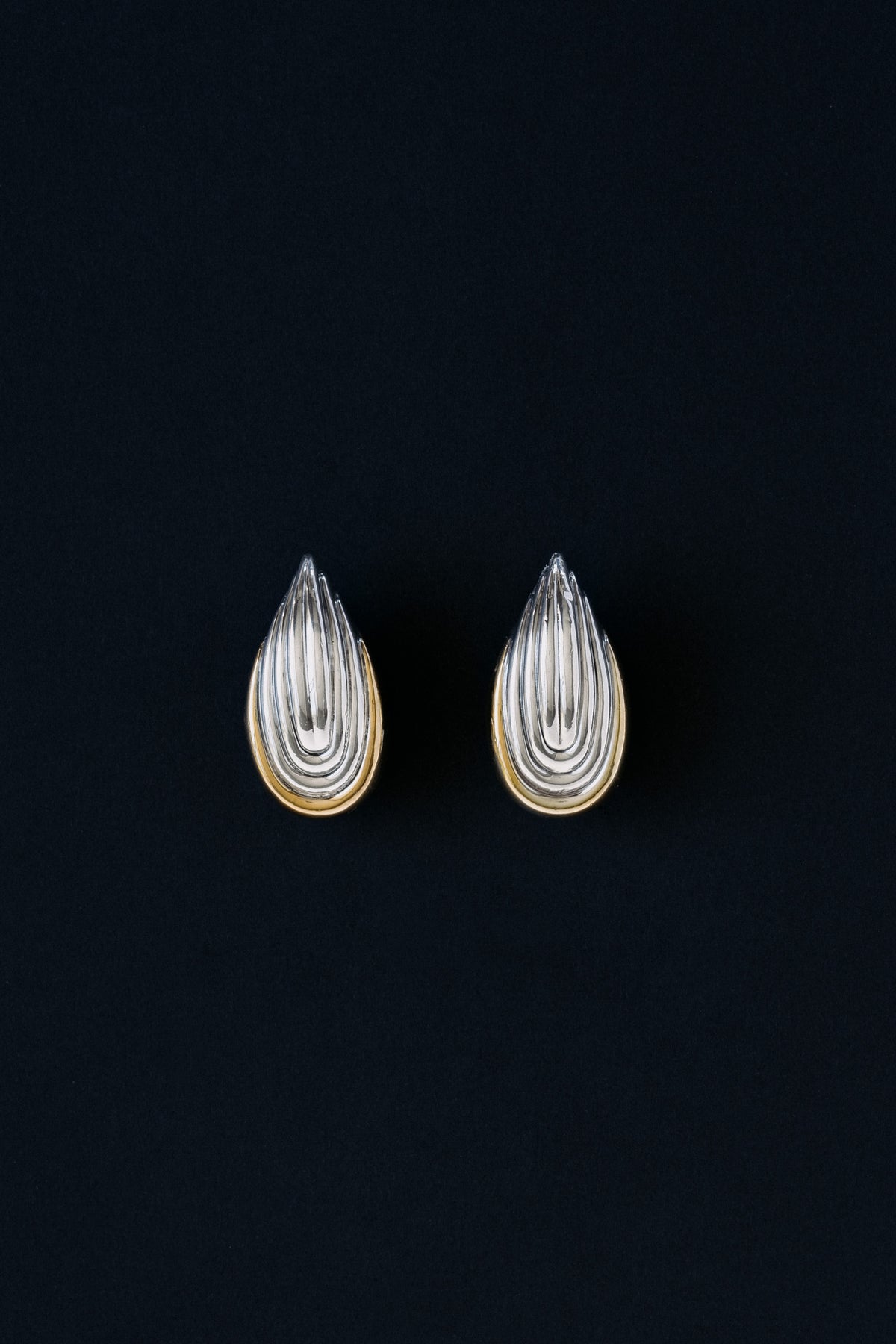 Vintage two-tone sterling silver fluted shell clip earrings, front view on black background